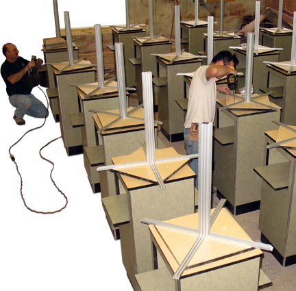 Two men collaborating at a large workspace filled with numerous desks, focused on their tasks and projects.